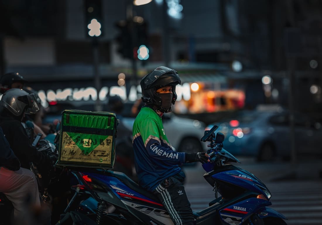 Entregadores de moto à noite em avenida movimentada