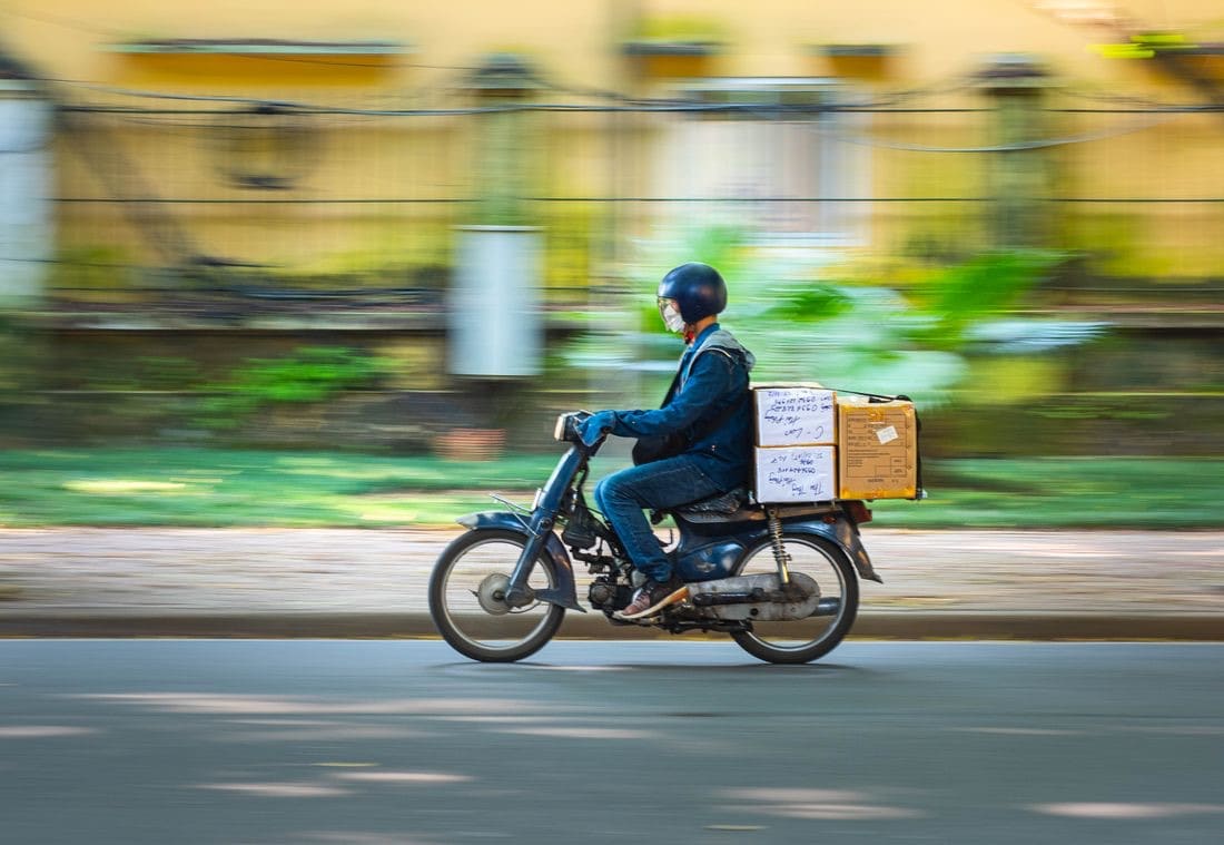 Moto de entrega com baú em movimento, foto panorâmica